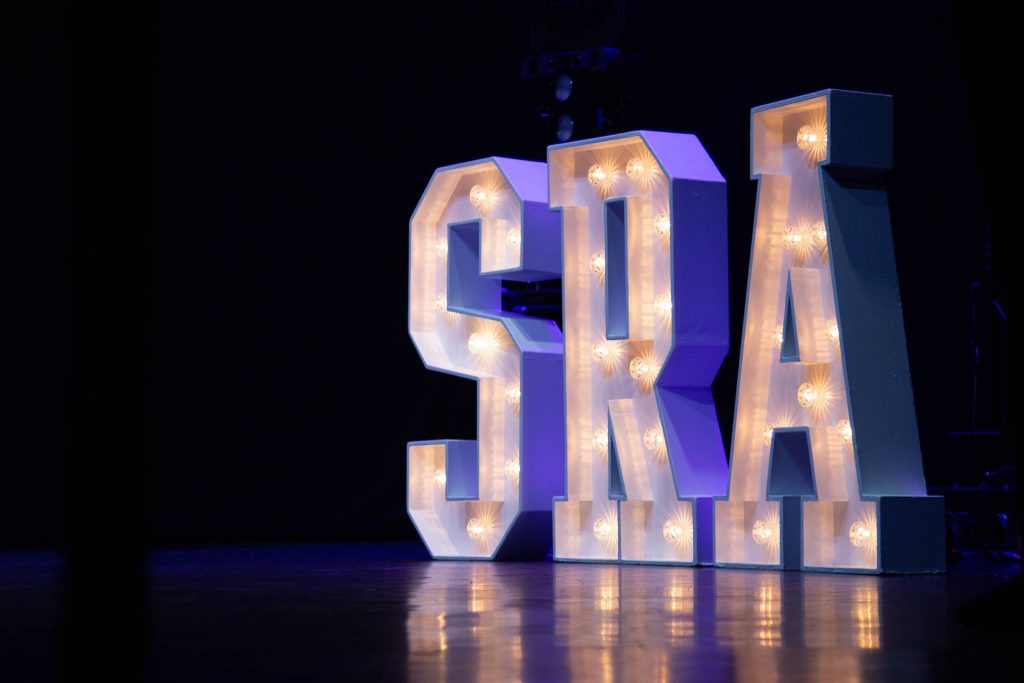 Large illuminated SRA letters on stage
